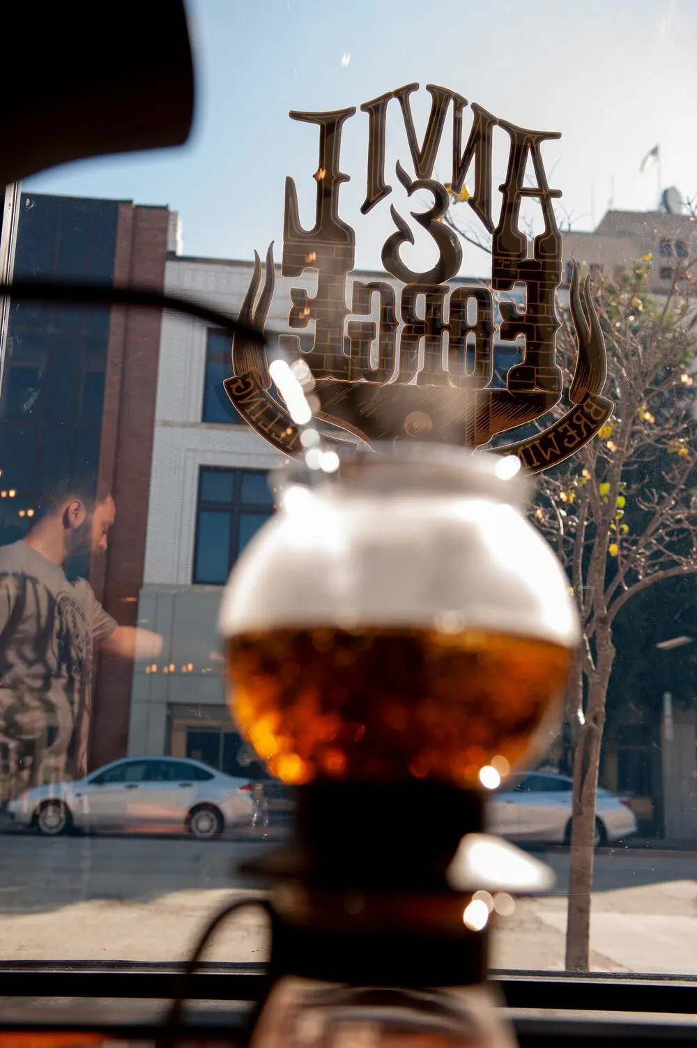 Anvil & Forge glassware beside a sunlit brewery window